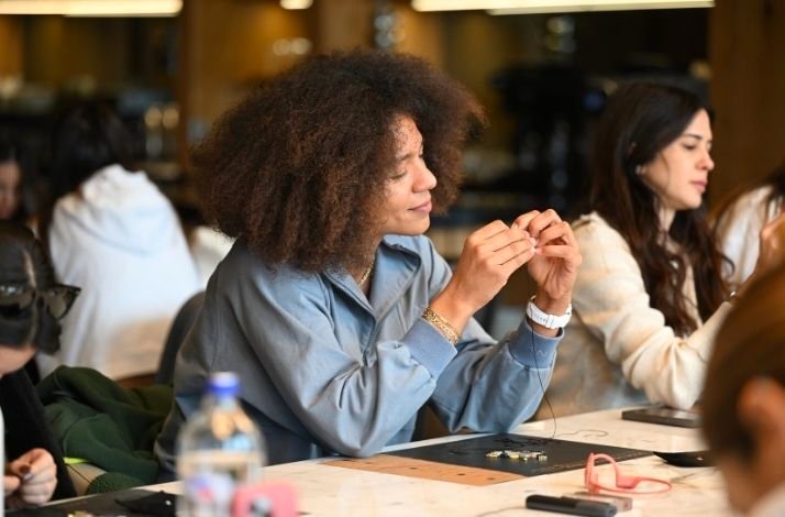 A girl smiling as she creates a unique natural stone bracelet in an exclusive 90-minute workshop with Pia Yüli.