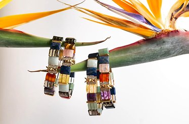 One-of-a-kind natural stone bracelets hanging from exotic  plant leaves for promotional photo.