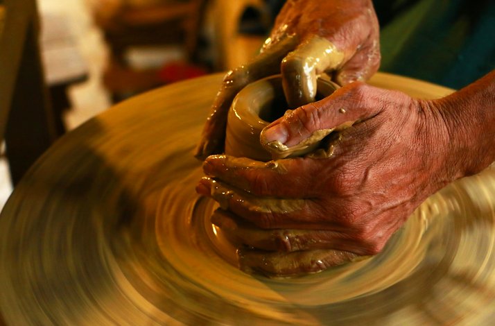 A close up of hands working with clay on a potter's wheel.