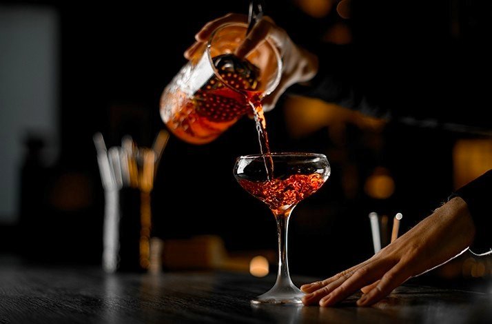 A bartender pours a cocktail from one glass into another at La Factoria.