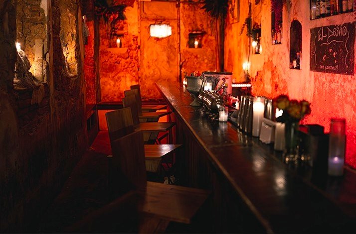 A row of chairs at a table against the wall in the red light of La Factoria.