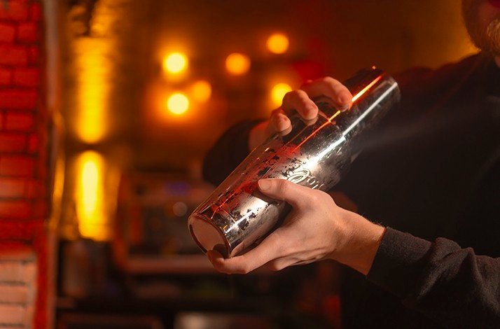 A bartender shakes a cocktail in a shaker at La Factoria.