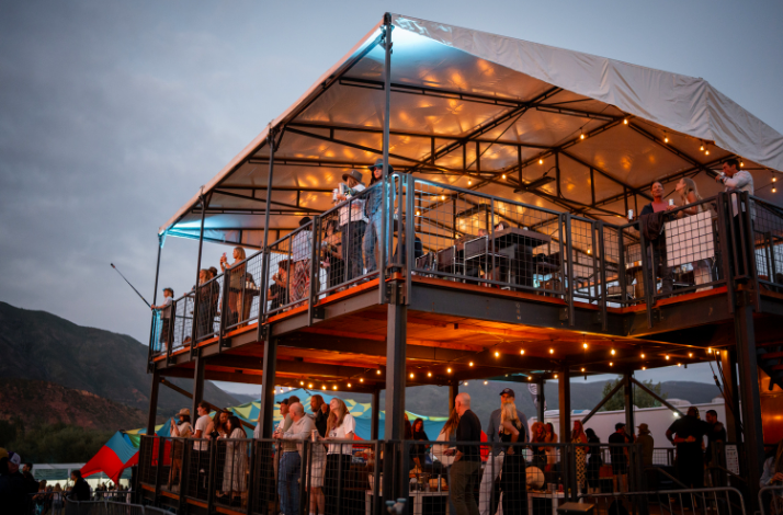 Several spectators on the private Mastercard Cabin with elevated views of the stage at Up in the Sky Festival.