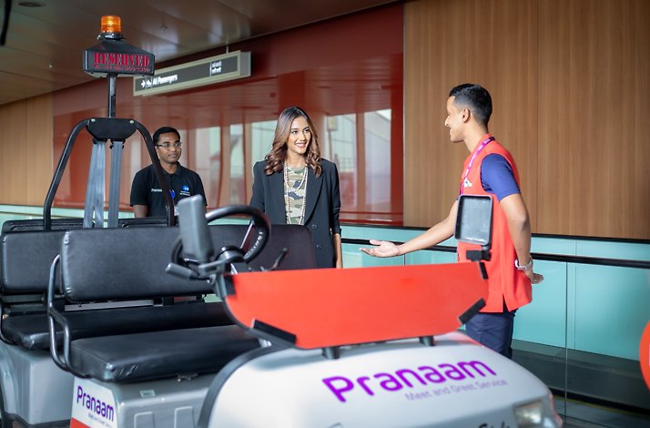 The employee points out to the woman a Dedicated Branded Buggy from Pranaam Meet & Greet services.
