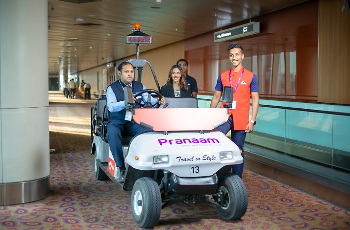 A woman waits for a ride on a Dedicated Branded Buggy to the boarding gate.