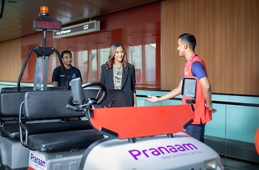 The employee points out to the woman a Dedicated Branded Buggy from Pranaam Meet & Greet services.