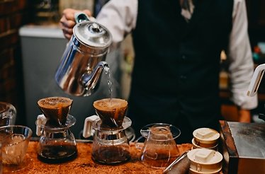 A person carefully pours tea into a filter, preparing a fresh brew from Divino Cafe Especial