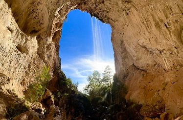 Canyon walls shaping an oval with the view on a blue sky and trees.