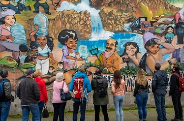 People looking at street art on the wall.