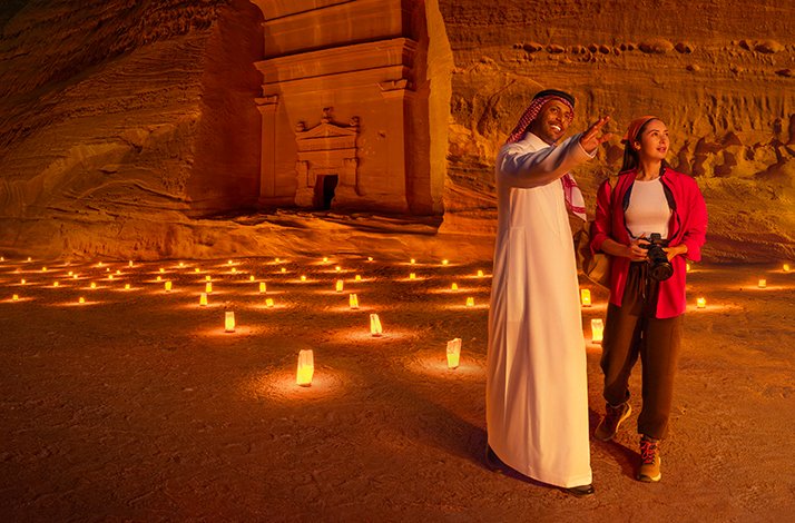 Abdulaziz Albalawi, a native Saudi storyteller showing a woman Hegra and the candles on the sand.