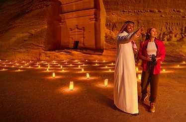 Abdulaziz Albalawi, a native Saudi storyteller showing a woman Hegra and the candles on the sand.