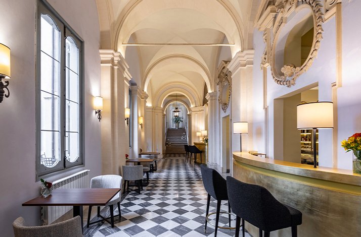 A long hallway featuring a checkered floor and several chairs lined along the sides.