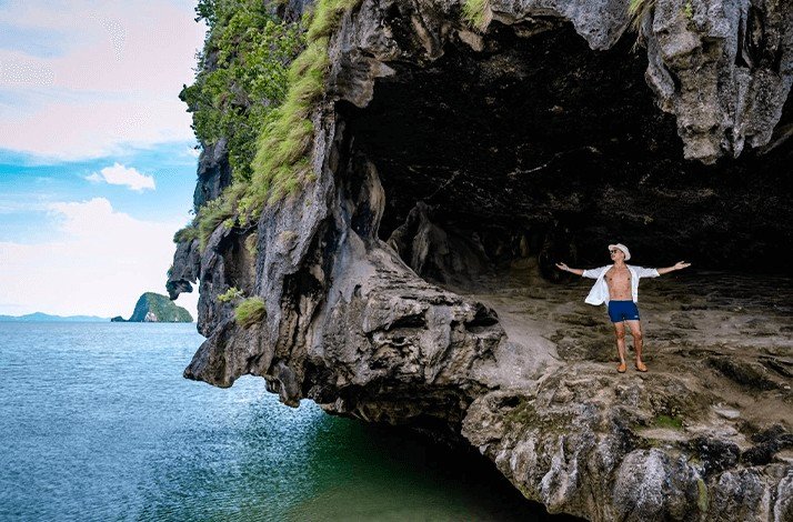 A man stands confidently on a rock located in James Bond island