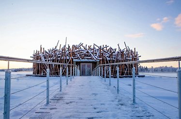 A wooden walkway leads to the Ecolyx Arctic Bath, surrounded by snow