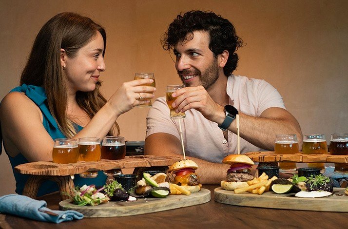 A couple enjoying a small menu at Cervecería Tulum Brewery Restaurant with different Pints