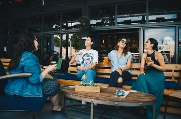 Four friends enjoying a moment together while sitting on a bench in a restaurant