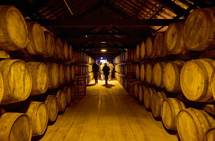 A man walks along an extended hallway filled with stacked barrels at the Midleton Distillery.