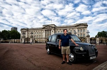 A tourist posing for the phono near the Buckingham palace standing by the black cab