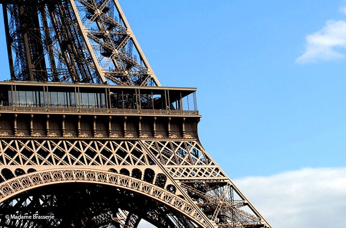 Close view of the Eiffel Tower against a blue sky.
