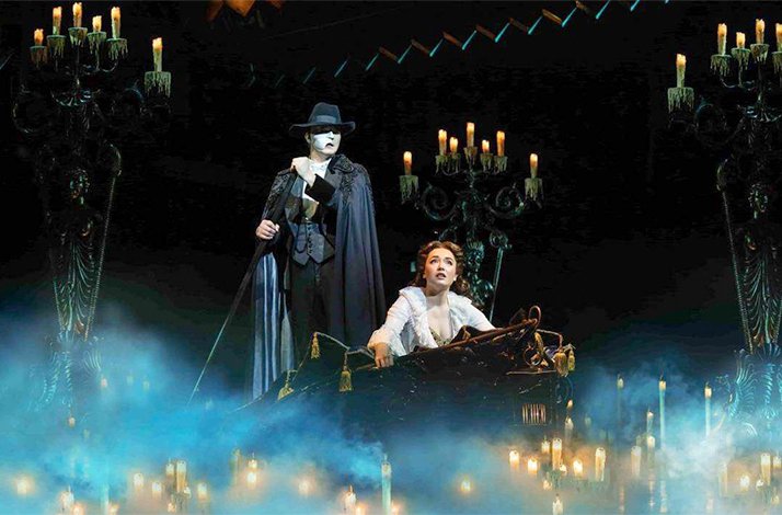 The Phantom standing over Christine in a candlelit, mist-filled gondola scene from The Phantom of the Opera.