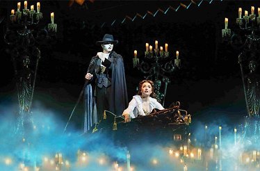 The Phantom standing over Christine in a candlelit, mist-filled gondola scene from The Phantom of the Opera.