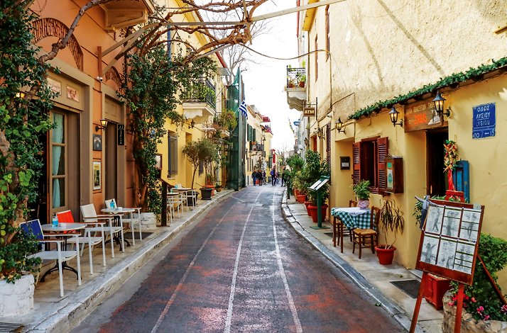 A narrow street with small cafes and shops on both sides of the road in Plaka, Athens.