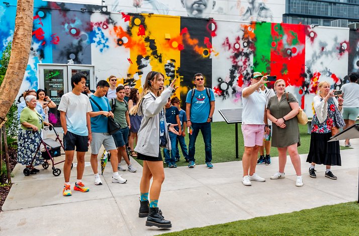 A woman guide telling people about the outdoor mural gallery and street art museum Wynwood Walls.