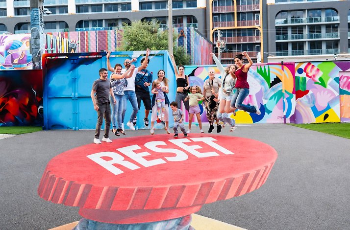 People jumping over the 'Reset' graphic art at museum Wynwood Walls.