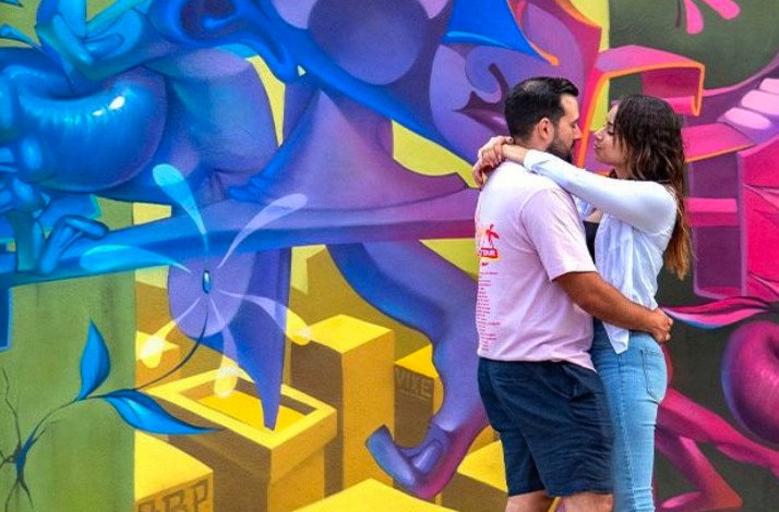 A couple poses in front of a wall art at the museum Wynwood Walls.