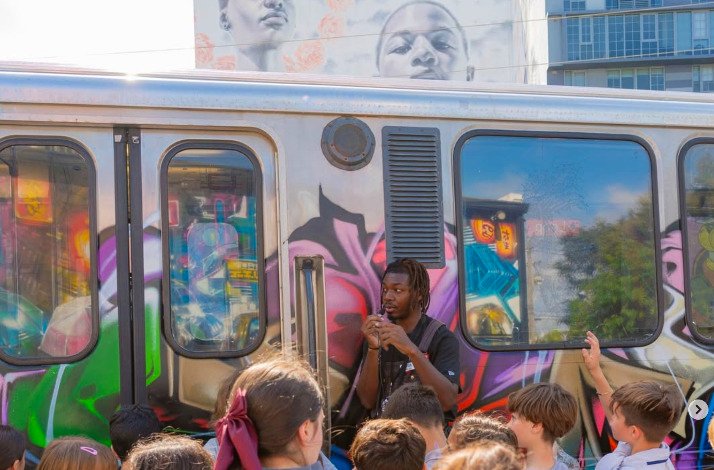A man standing next to the train with a graffiti on it.