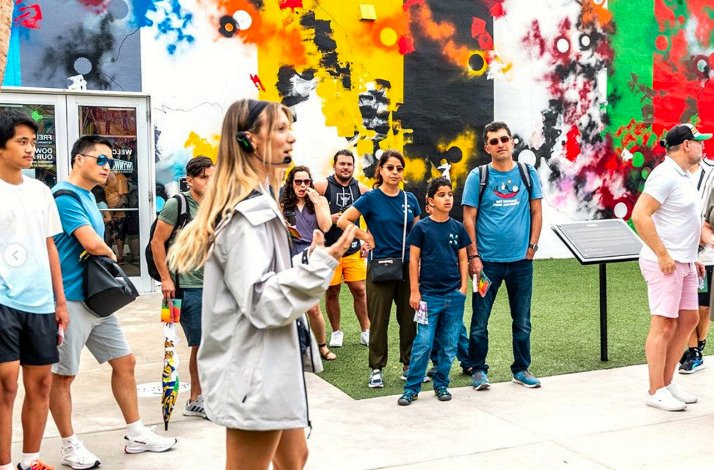 A woman guide telling people about the outdoor mural gallery and street art museum Wynwood Walls.
