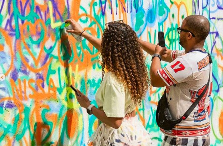 A man and a woman drawing graffiti on the wall at Wynwood Walls Museum.