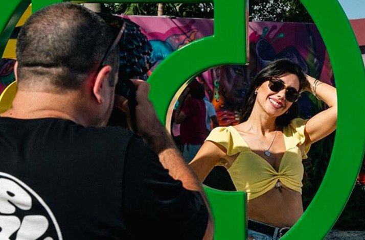 A man taking a picture of a woman standing next to art installation at Wynwood Walls Museum.