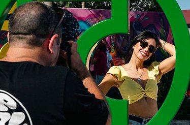 A man taking a picture of a woman standing next to art installation at Wynwood Walls Museum.