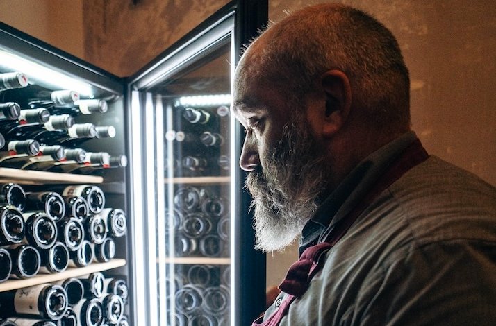 A man looks at bottles of wine in a refrigerator at The Winery.