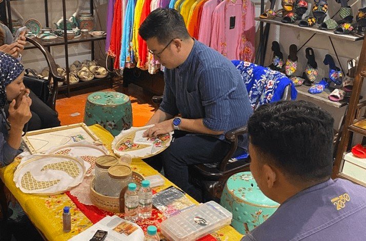Kenny Loh showing embroidery to clients on his private showroom.