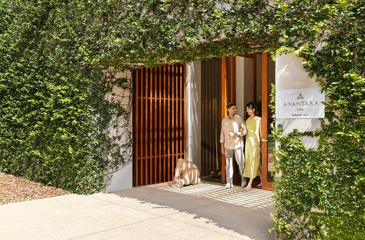  A man and woman stand together in front of a modern building, smiling and dressed in casual attire.
