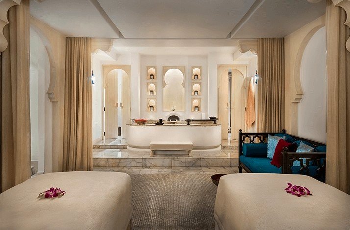 A serene spa room featuring two massage beds and a luxurious bathtub, creating a tranquil atmosphere for relaxation.