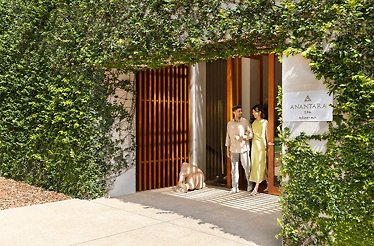  A man and woman stand together in front of a modern building, smiling and dressed in casual attire.