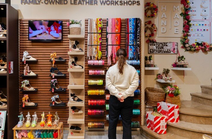 A woman stands in front of a colorful shoe display, examining various styles and designs available for purchase.