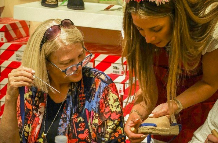 A woman assists an older woman in putting on her shoe, demonstrating care and support.