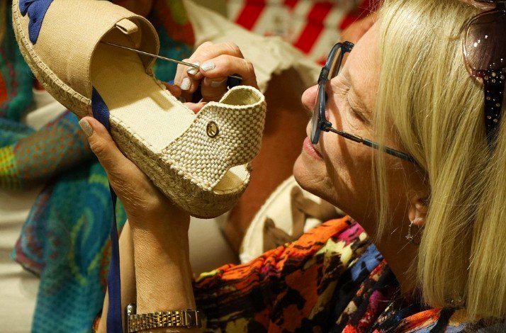  A woman is bending down to put on a pair of shoes in a bright, well-lit room.