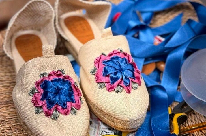 A pair of white shoes adorned with blue and pink floral patterns.