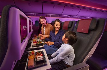 A flight attendant watches as a family enjoys a meal during a discounted flight on Qatar Airways.
