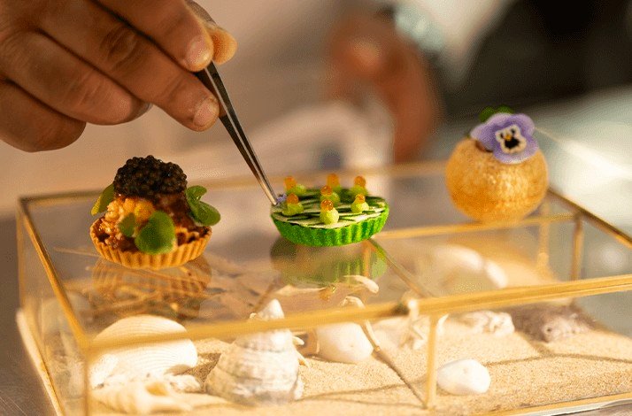 Chef is adding a final touch to refined Thai fusion food to be served on a glass case at Su Va Na Restaurant.