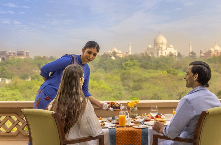 A couple enjoying their balcony lunch at the Oberoi Amarvilas, Agra with a view on Taj Mahal.