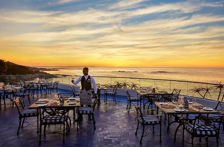 A waiter sets tables at The Twelve Apostles Hotel and Spa at sunset.