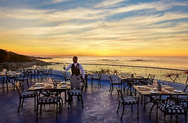 A waiter sets tables at The Twelve Apostles Hotel and Spa at sunset.