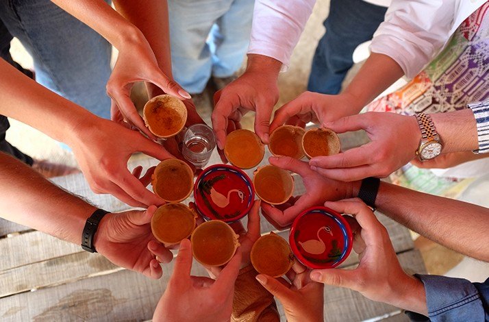 A group of people raise traditional cups in a celebratory toast.
