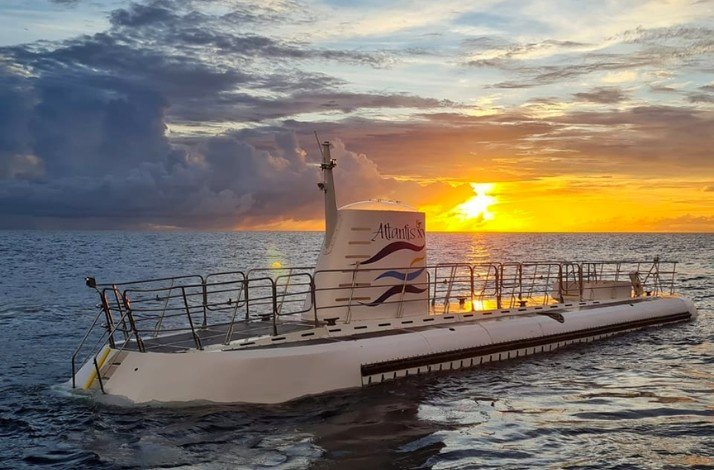 The Atlantis Submarine floats on the surface of the ocean at sunset, ready to begin its underwater journey
